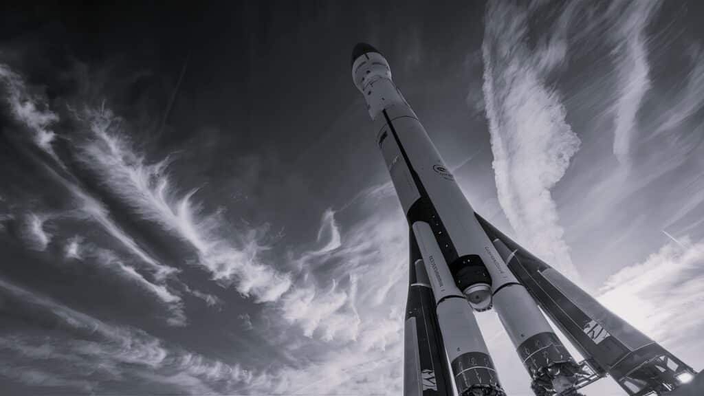 Photo en noir et blanc d'une fusée prise d'en bas, vision sur le ciel.